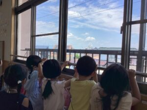 「頑張れー！」「外国まで頑張ってね」ツバメがびっくりしないように、小さな声で応援している子どもたち。